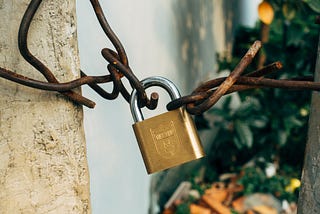 Brass padlock on brown metal fence