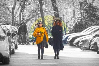 Chicas caminando entre coches