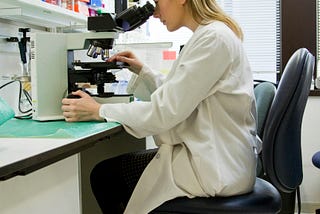 A lady scientist poring over a microscope in the lab