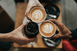 Three cups of coffee being held in a cheers pose