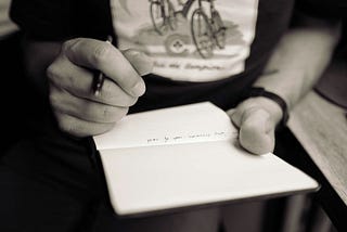 A person’s hands clutching a pen and notebook