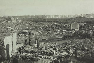 Soldiers survey and move through destroyed buildings