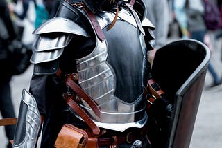 A man standing with armor on and many people behind and beside him.