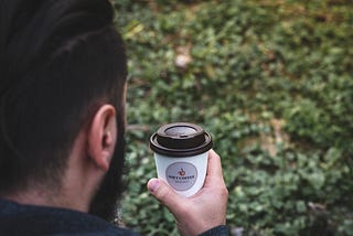 A man carrying one to-go cup of coffee