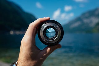 Hand holding a camera lens on a scenic view