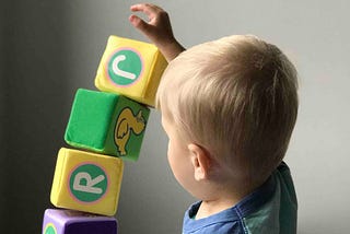 Small child stacking blocks with letters on them