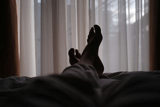 A pair of legs are visible resting on a bed.