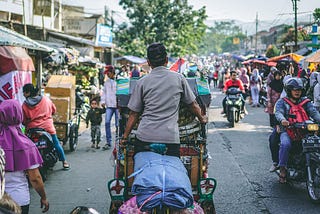 Jalan sibuk dengan becak dan sepeda motor dan banyak orang
