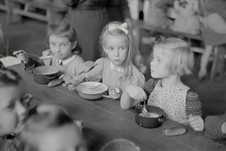 Young children eating breakfast in the cafeteria. Photo from the 30s?