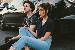 A couple sitting next to each other and listening to music from their collaborative playlist