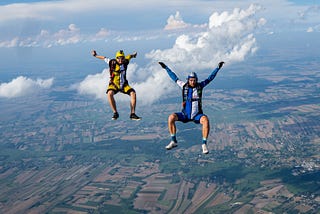 Two men facing camera with arms and legs spread open while skydiving