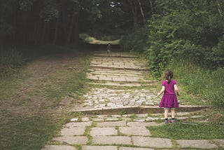 Una niña pequeña observa a otro pequeñajo entrar en un bosque que no mola nada.