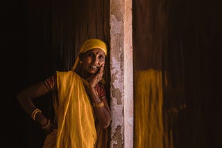 An Indian woman leans against a concrete pillar