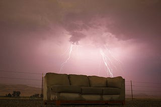 A green sofa sits outside as two bolts of lightning strike in the background. A new study reminds us of the perils of sedentary behavior (such as prolonged sitting).