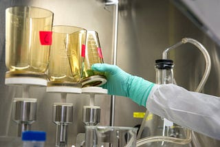 Scientist reaching for beaker of chemicals in laboratory (PFAS, PFOA)