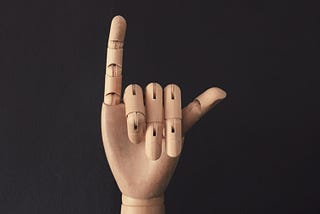 Hang ten sign on a wooden model hand