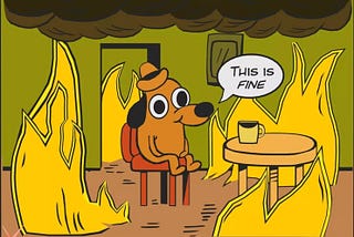 “This is fine”. Dog sitting next to a table, while surrounded by flames.
