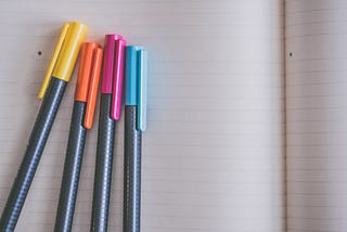 colorful pens on white lined paper