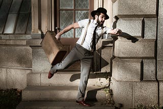 Bearded man rushing with cap on head and box in hand