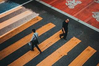 Strangers pass on a crosswalk across a street