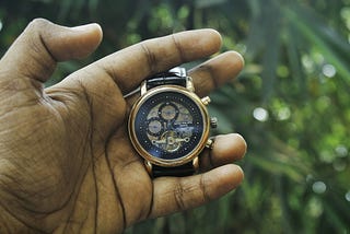 Close-up of a hand holding a wristwatch, symbolizing time passing and waiting for the right moment.