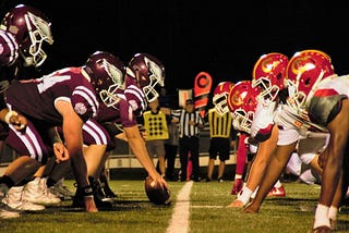 Two American football teams lined up, facing each other across the line of scrimmage.