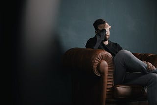 A man sitting on a couch with his head in his hands