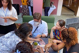 A group of six people sit around a table doing an arts and crafts activity.