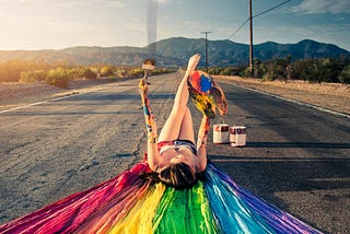 woman painting a rainbow on a country street
