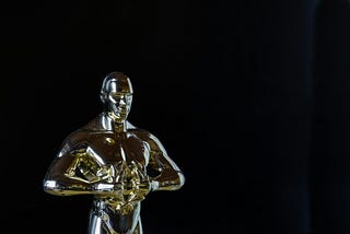 A gold trophy that looks like an Oscar. However, it is of a slightly different design where the figure has different features and is holding a laurel instead of a sword.