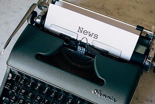 Olympia typewriter with sheet of paper inserted. The word ‘News’ is typed at the top of the paper.