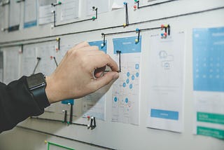 hand using string to connect points on charts pinned to a bulletin