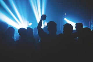 A guy with cup in the air at a night club