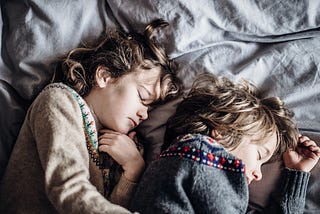 Two young children asleep in the bed