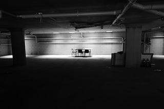Empty concrete basement with table and chairs