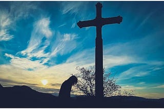 A person praying for forgiveness at the foot of a cross