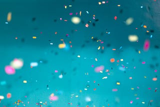 A bunch of colorful confetti on a teal background.