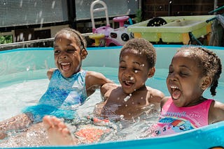 three black children playing in a pool