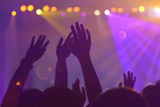 Hands raised in a crowd in front of a stage