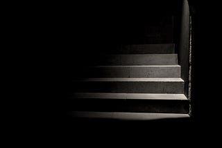 A partially lit staircase leading to darkness