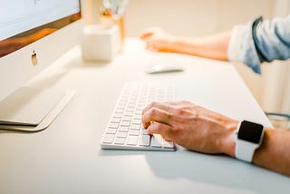 Man typing on Apple desktop computer.