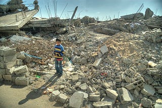 A boy of 8 or 9 stands on a pile of rubble in Gaza