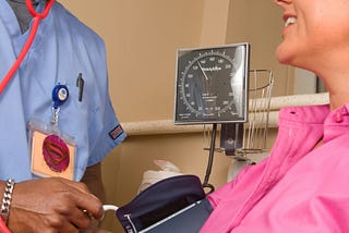 A male nurse checks a patient’s blood pressure.