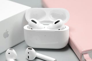 Airpods! Flanked by a pink notebook and the Apple product box.