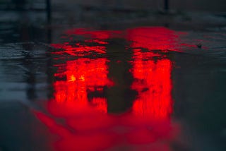 Red light reflected on a damp road surface