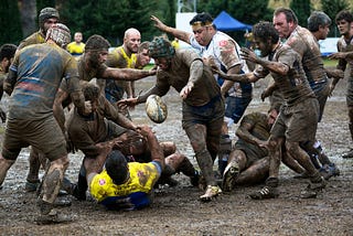 A group of rugby players competing in muddy conditions.