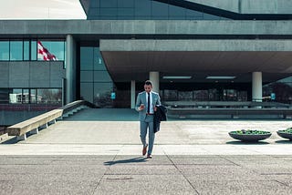 Image of a man, smartly dressed and leaving a building.