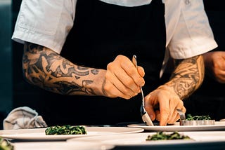 A chef plating food in a restaurant kitchen.