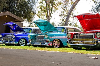 Three antique cars with their hoods up