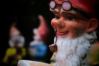 Garden gnome statue smoking a pipe with a book in his hands